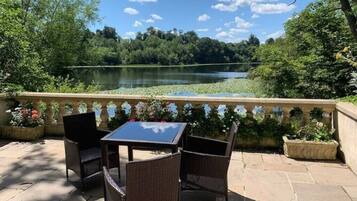 An outdoor patio with wicker furniture and a view of a lake.