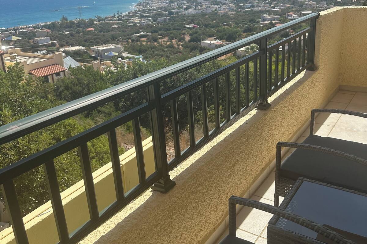 A balcony with a view of a coastal town, a mountain, and the sea.