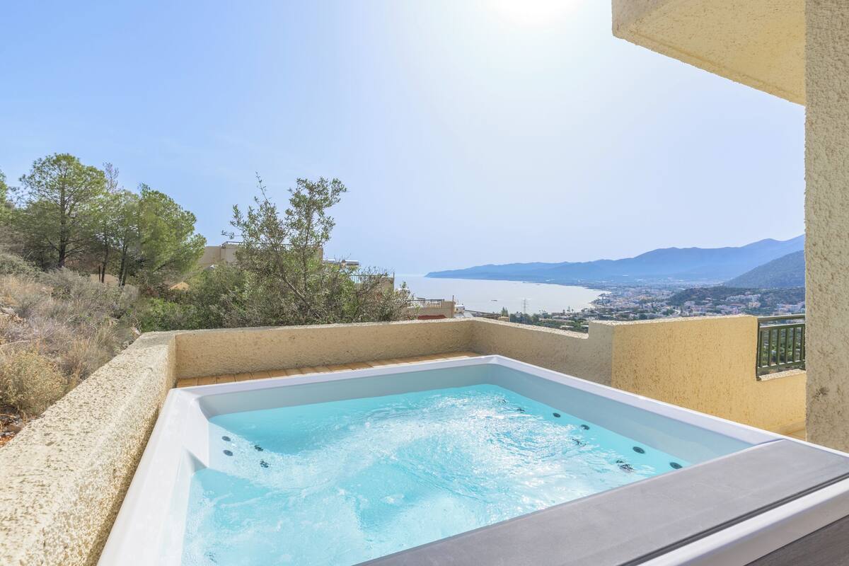 A hot tub with a clear view of a coastal landscape and mountains in the background.