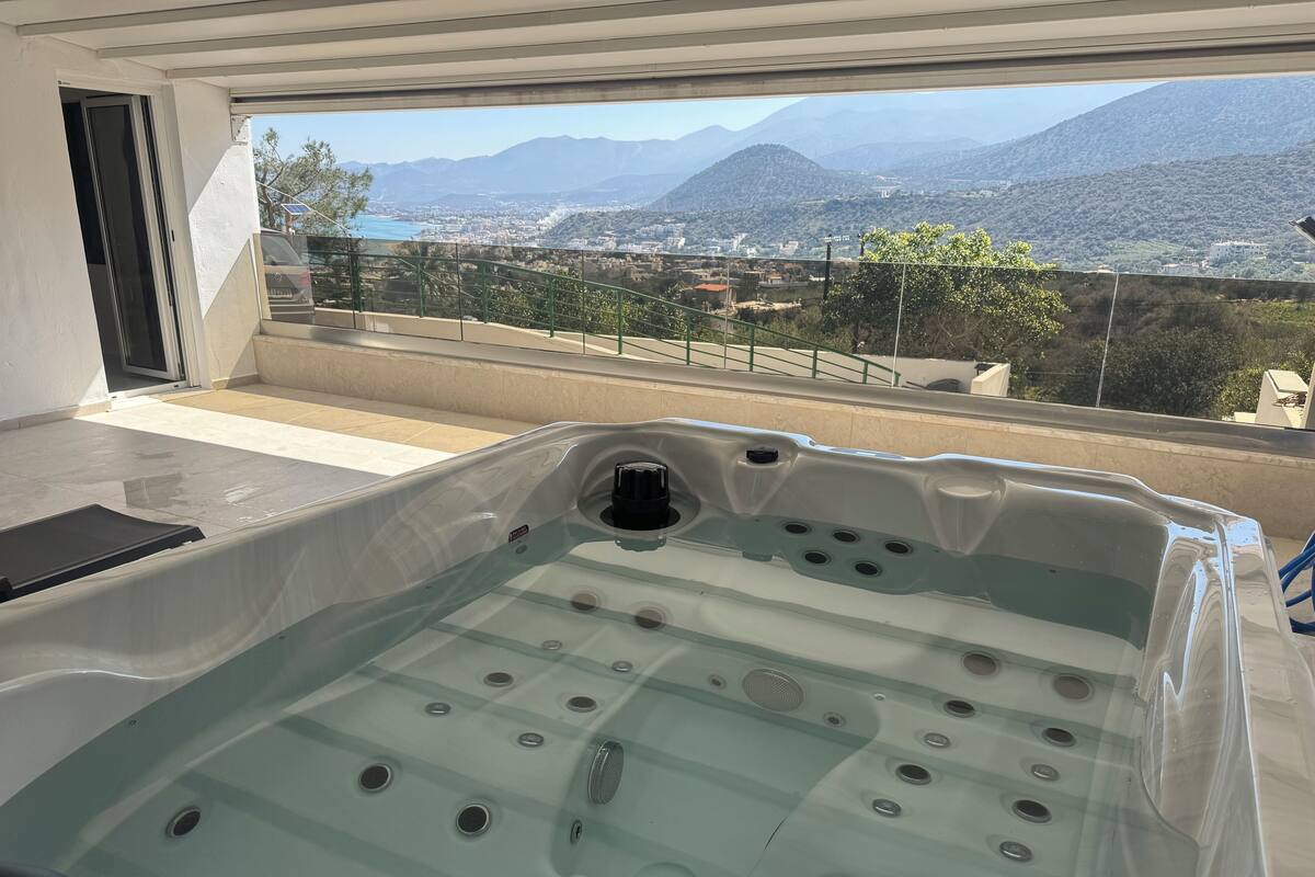 A hot tub with a view of mountains and a cityscape.