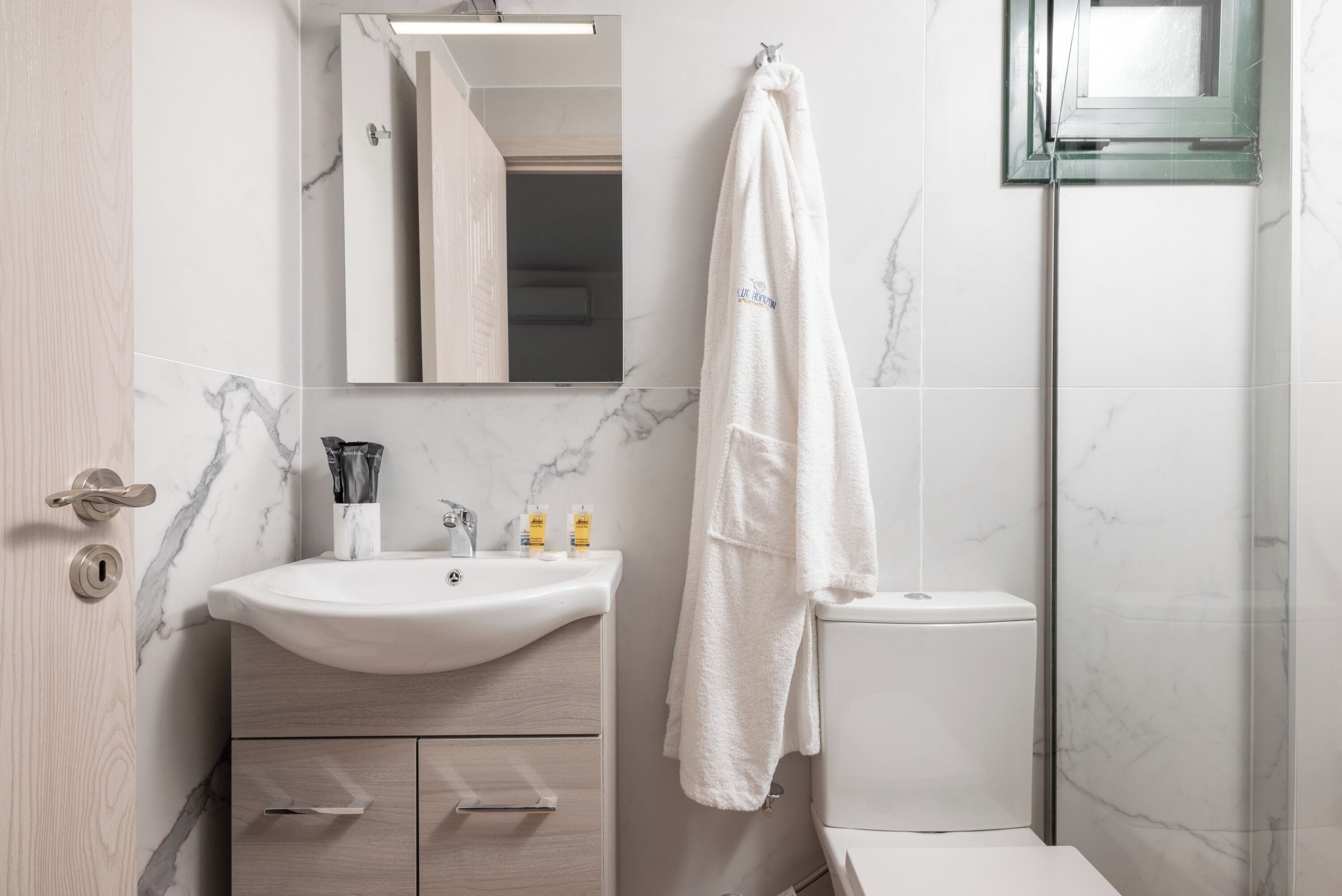 Un baño moderno con lavamanos de mármol, inodoro y cabina de ducha de vidrio.