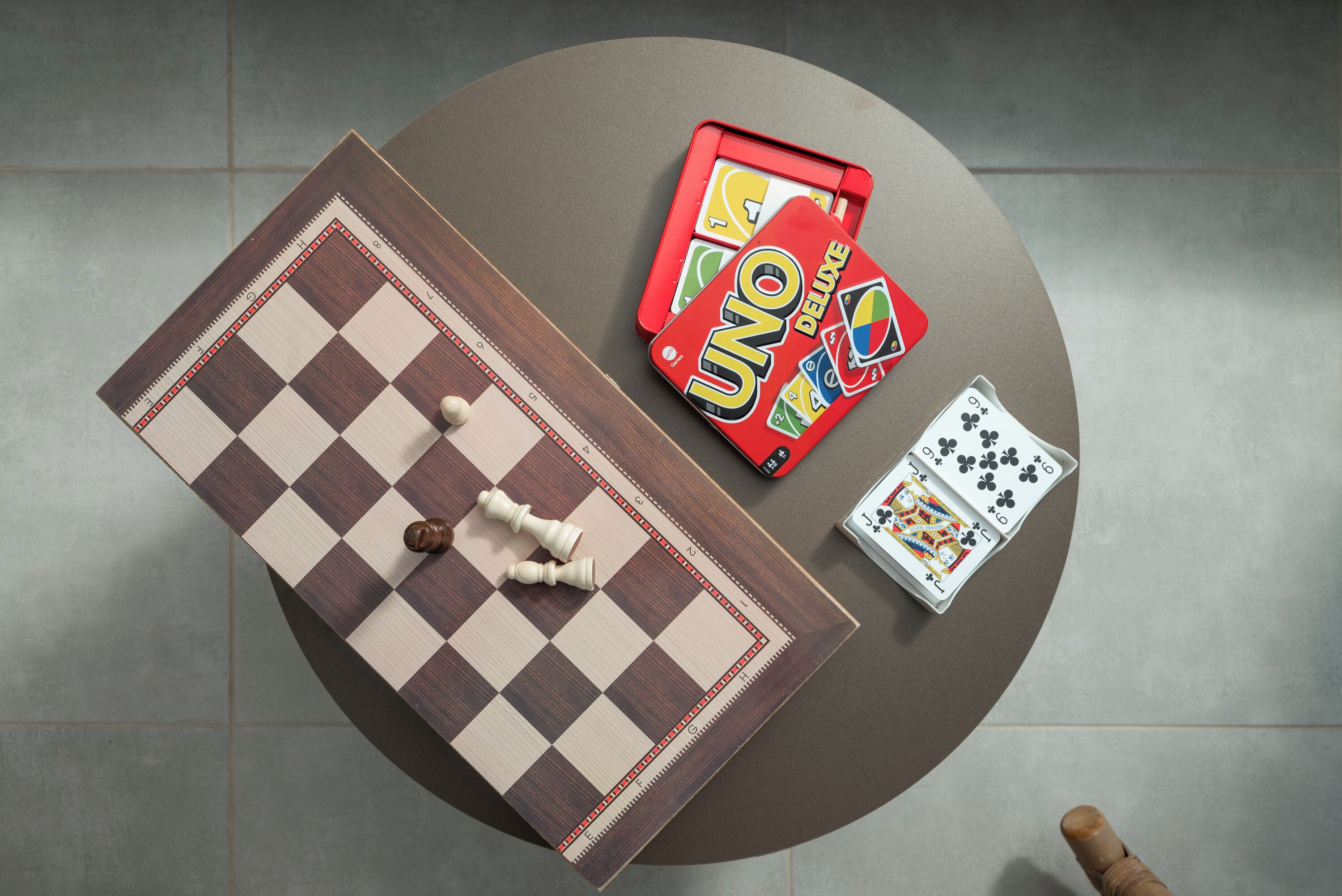 A checkered board game setup with a chessboard, UNO cards, and playing cards.