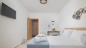 Habitació d'hotel amb un llit, televisió de pantalla plana penjada a la paret, una taula de nit amb una làmpada i una decoració mural.