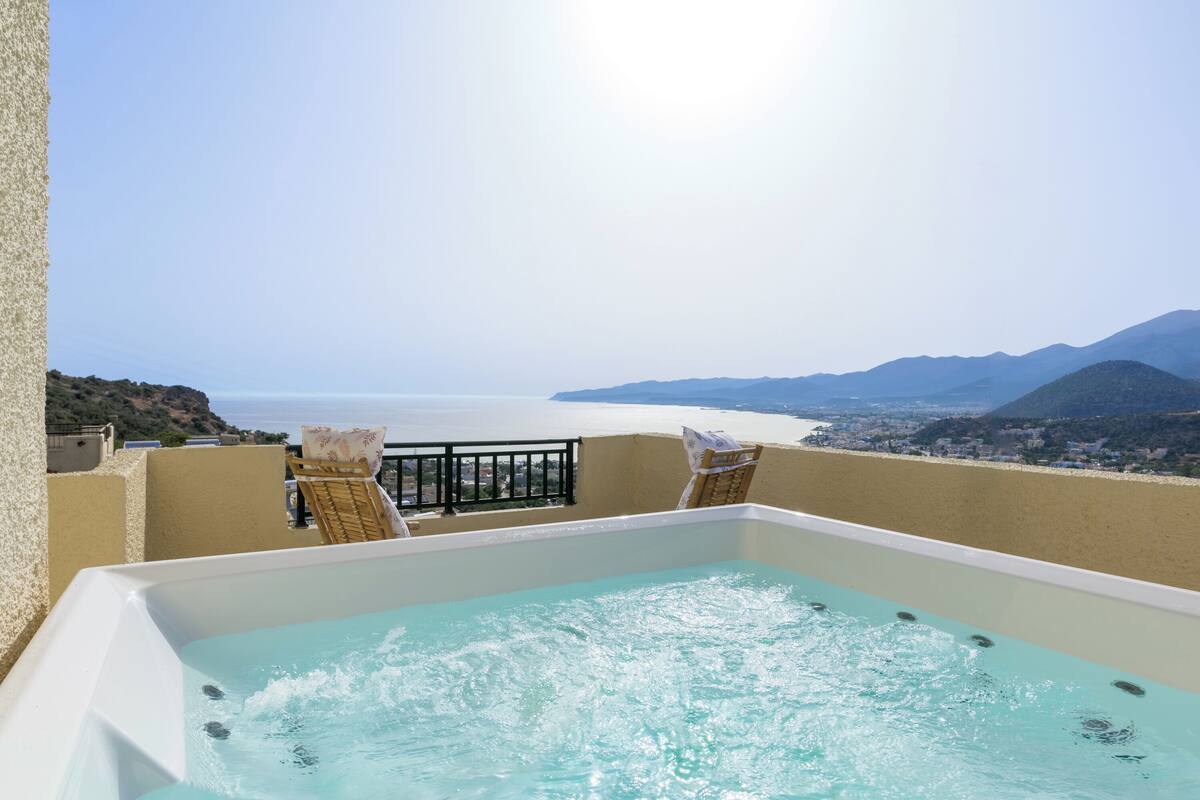 A hot tub with a view of the sea and mountains.