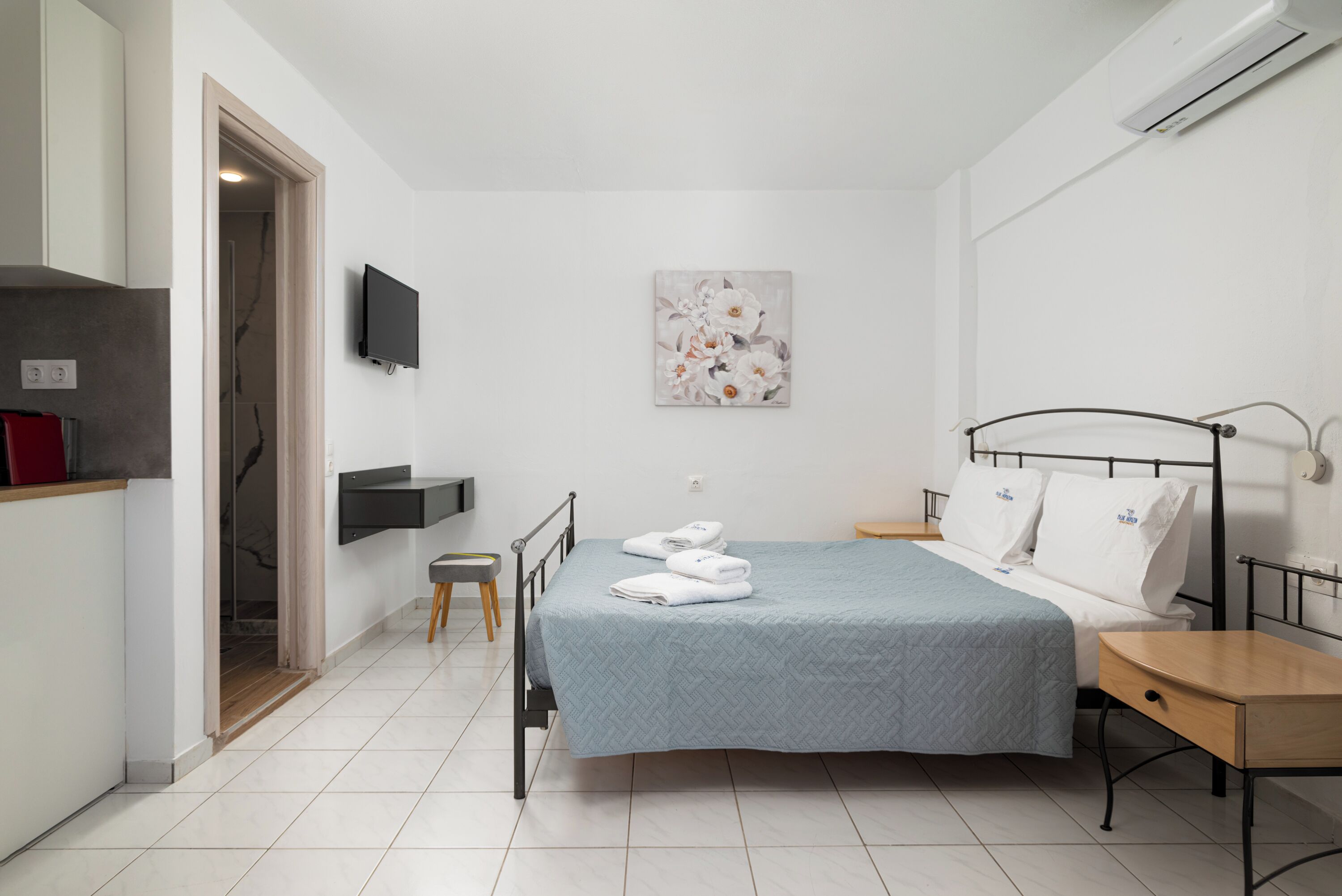 Un dormitorio moderno con una cama, un televisor y un cuadro en la pared.