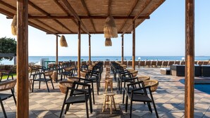 A beachside patio with rows of chairs and tables, a pool, and a view of the sea. - Costa Lindia Beach Resort (Rhodes)