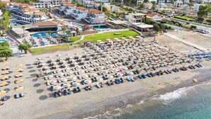 A beach resort with numerous sun loungers and umbrellas, a swimming pool, and a view of the surrounding residential area. - Costa Lindia Beach Resort (Rhodes)