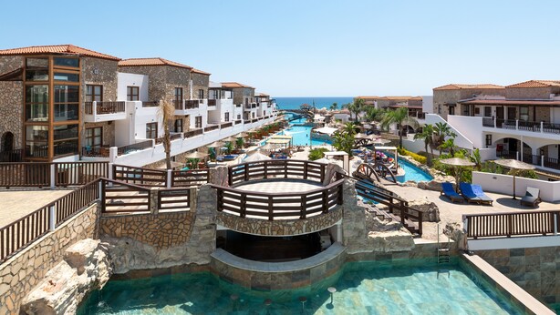 A resort with a central pool, multiple balconies, and a view of the ocean. - Costa Lindia Beach Resort (Rhodes)