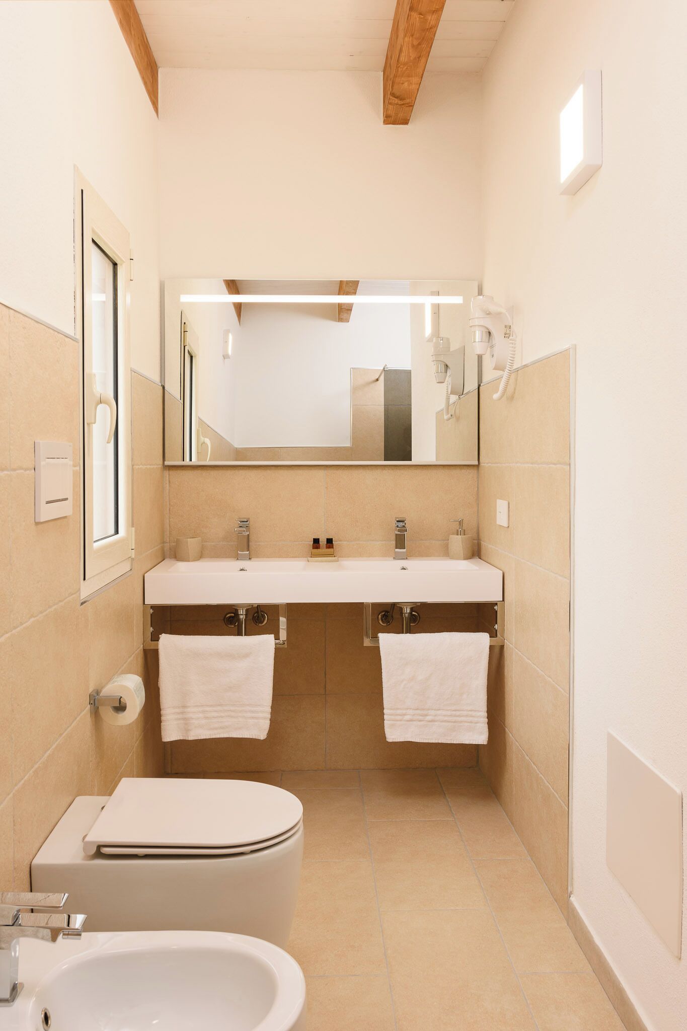 A modern bathroom with two sinks, a toilet, and a bathtub.