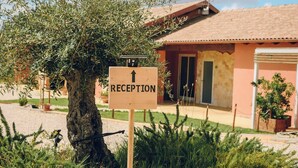 A reception sign with an arrow pointing upwards, a tree, and a building with a tiled roof.