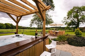 A wooden pergola with a hot tub and outdoor seating area. - Orchardleigh Castle East, Orchardleigh Estate
 (Frome)