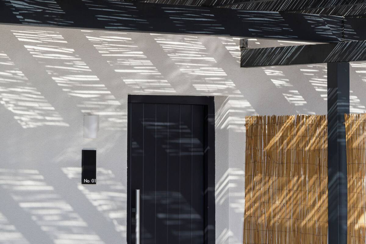 A modern indoor pool area with a black door, a glass wall, and a bamboo wall.
