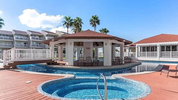 A pool area with a gazebo, palm trees, and a view of hotel buildings. - 3BR Beach Condo: : Private Balcony & Pool Access (South Padre Island)
