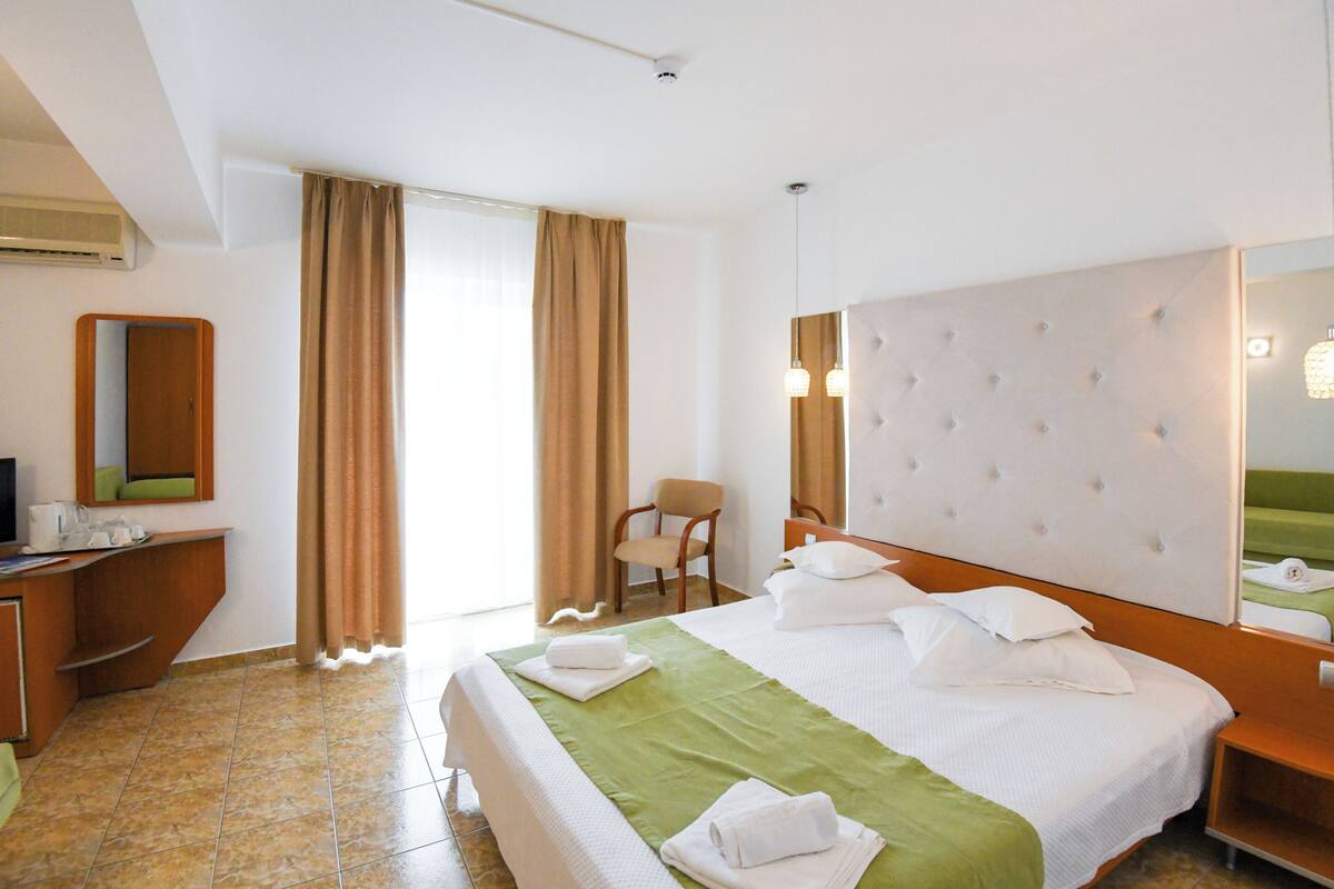 Une chambre d’hôtel avec un lit, une chaise, un bureau et un miroir.