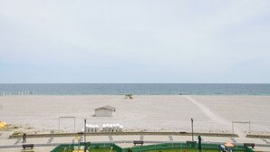 A beach with a paved walkway, benches, and a small building. - Complex Modern Mamaia All Inclusive (Constanta)