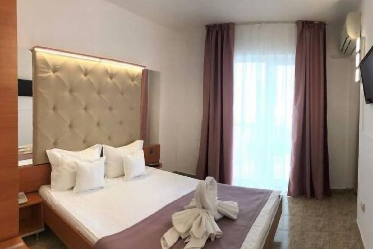 Une chambre d’hôtel avec un grand lit, un téléviseur à écran plat fixé au mur et un canapé dans un coin.