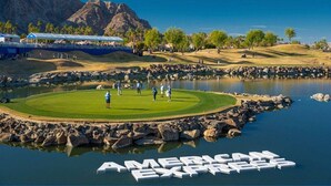 A golf course with a pond and the text 'AMERICAN EXPRESS' on the water. - Golfers' Paradise: Pool, Spa, EV Charger (La Quinta)