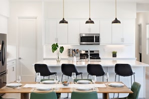 Een moderne keuken met witte kasten, een centraal eiland met zitplaatsen en hanglampen.
