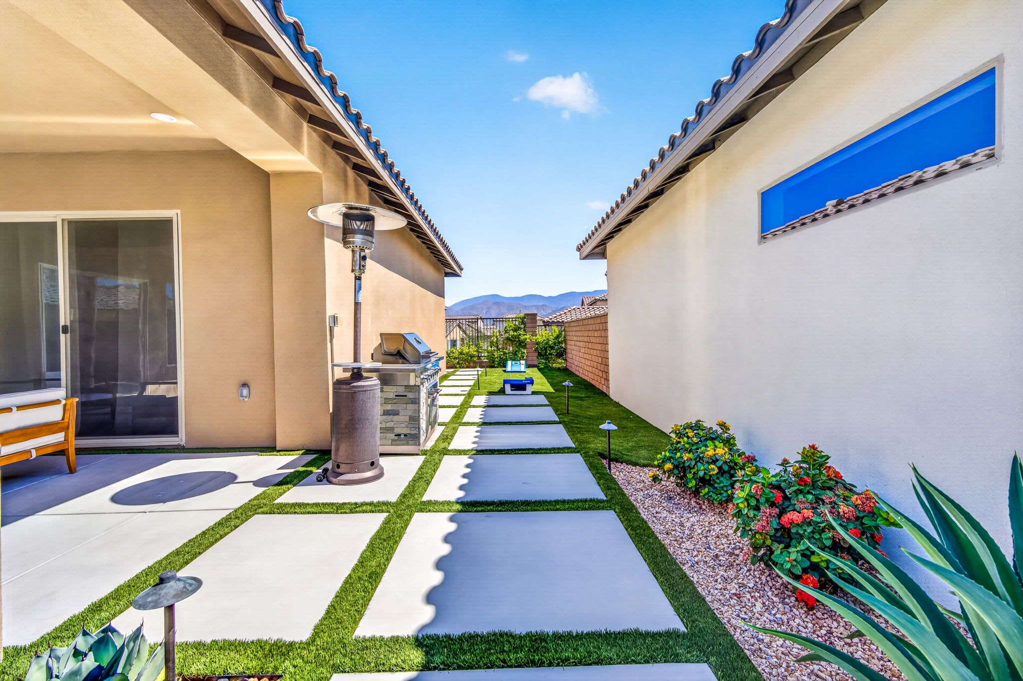 A patio area with a grill, outdoor seating, and a clear view of the mountains in the distance.