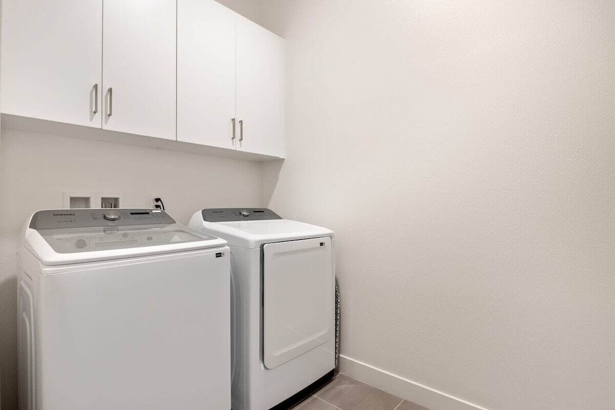 Un espace buanderie avec deux machines à laver blanches et un meuble de rangement au-dessus.