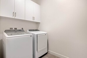 Un espace buanderie avec deux machines à laver blanches et un meuble de rangement au-dessus.