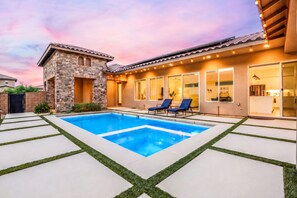 Une maison moderne dotée d’une piscine, d’une façade en pierre et d’un intérieur bien éclairé.