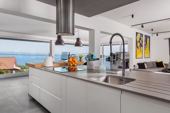 Una cocina moderna con una isla grande, electrodomésticos de acero inoxidable y vistas al mar.