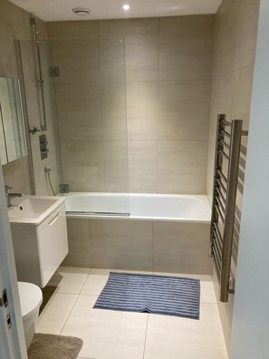 A modern bathroom with a bathtub, a sink, and a toilet. - Stunning 3-bed, 3-bath Apartment in Southampton (Southampton)