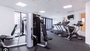 A gym with cardio machines, weight machines, and a large window providing natural light. - Stunning 3-bed, 3-bath Apartment in Southampton (Southampton)