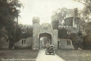 Un bâtiment historique doté d’une grande entrée en arc de cercle, d’une tour en pierre et d’un chemin menant à l’entrée.
