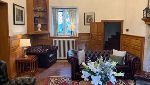 A traditional living room with leather sofas, a wooden cabinet, and a large window with curtains. - Orchardleigh Castle West, Orchardleigh Estate (Lullington)