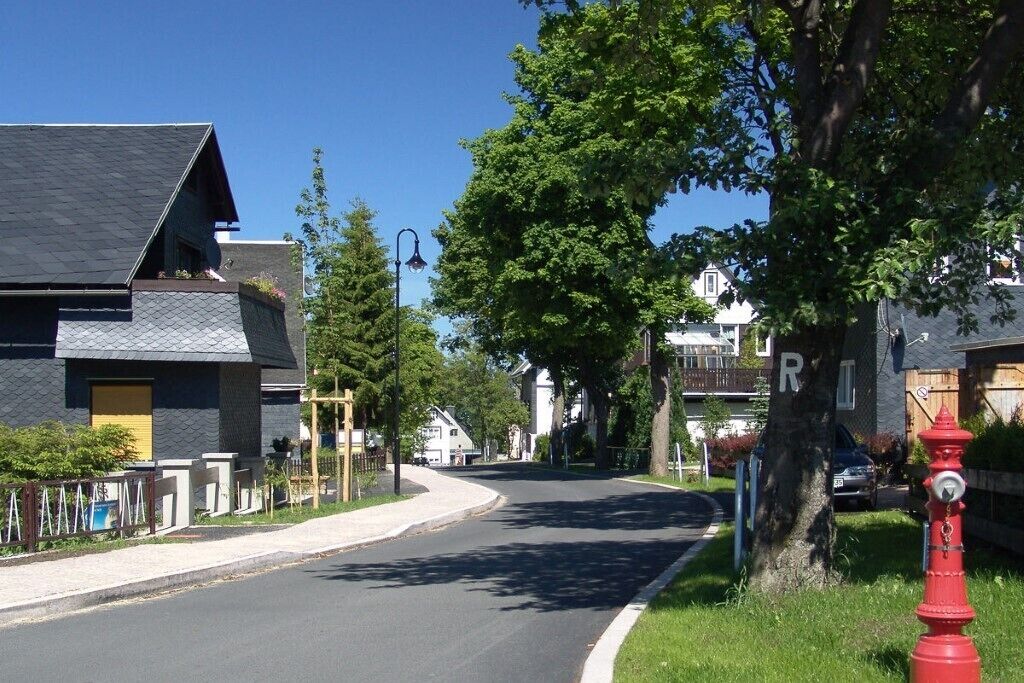 Eine Wohnstraße mit Häusern, einem roten Hydranten und einem strahlend blauen Himmel.
