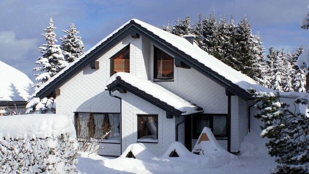 A snow-covered house with a sloped roof, multiple windows, and a chimney. - Vacation home, 98 sqm / sauna / 1 - 5 persons / 5 min. from the Rennsteig. (Neuhaus am Rennweg)