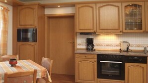A kitchen with wooden cabinets, a microwave, an oven, and a coffee maker. - Vacation home, 98 sqm / sauna / 1 - 5 persons / 5 min. from the Rennsteig. (Neuhaus am Rennweg)