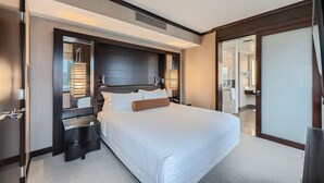 Una habitación de hotel moderna con una cama grande, un cabecero oscuro y un vestidor.