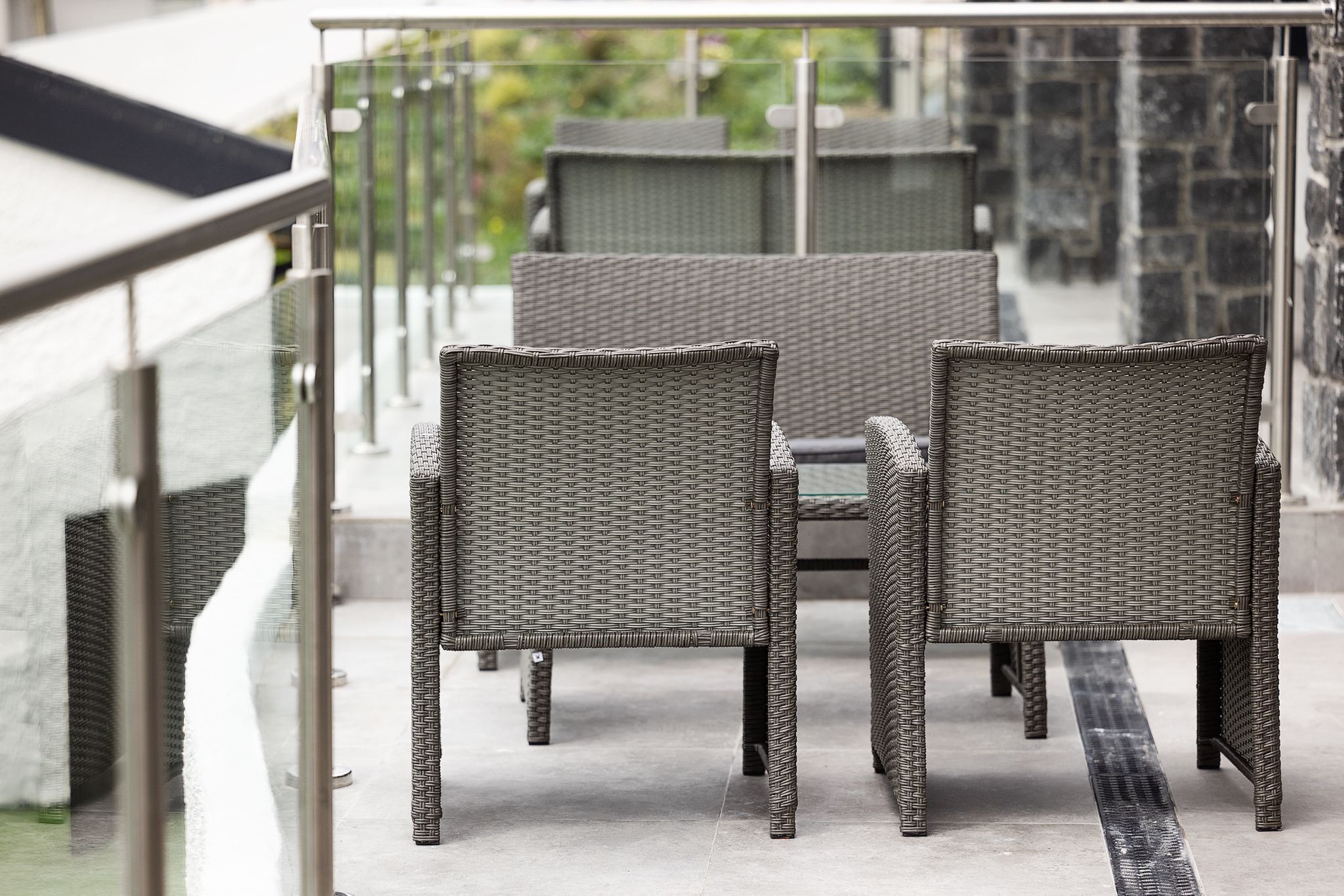 A balcony with wicker furniture and a glass railing.
