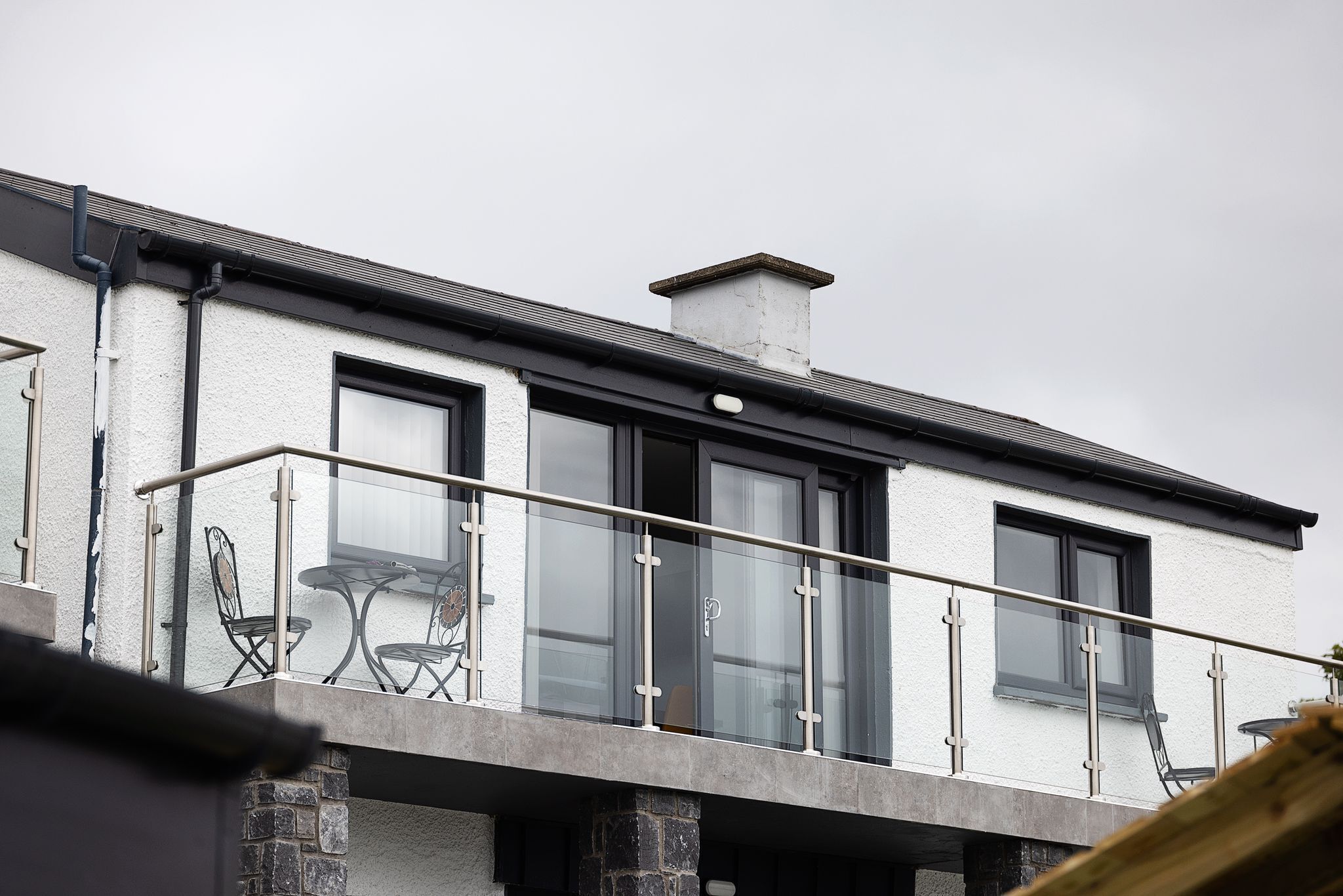 Een modern gebouw met een balkon, grote ramen en een stenen fundering.