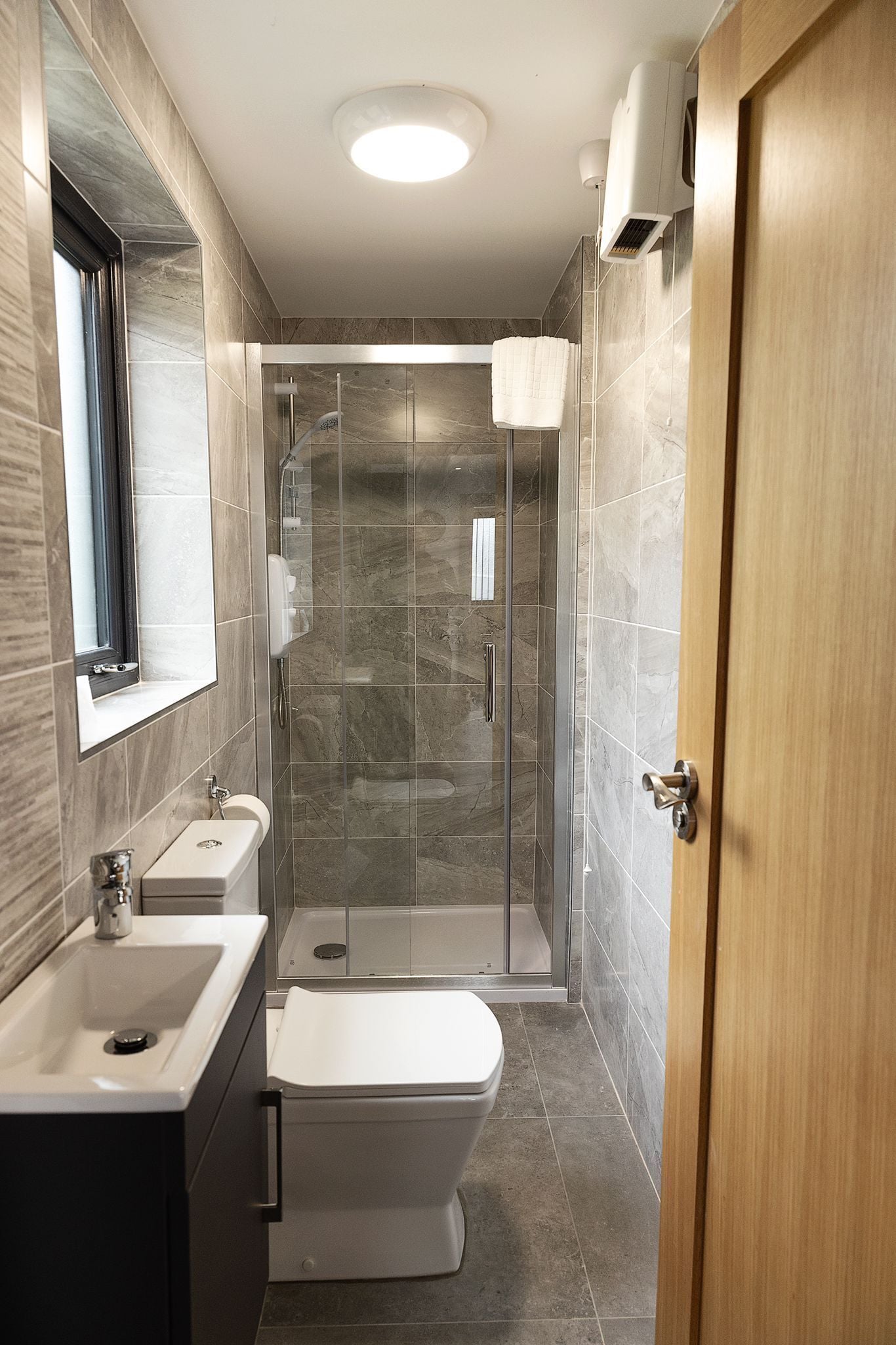 A modern bathroom with a glass-enclosed shower, a toilet, and a sink.