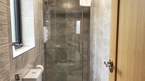 A modern bathroom with a glass-enclosed shower, a toilet, and a sink. -  Pierside Apartments Deluxe Accommodation (Portsalon)
