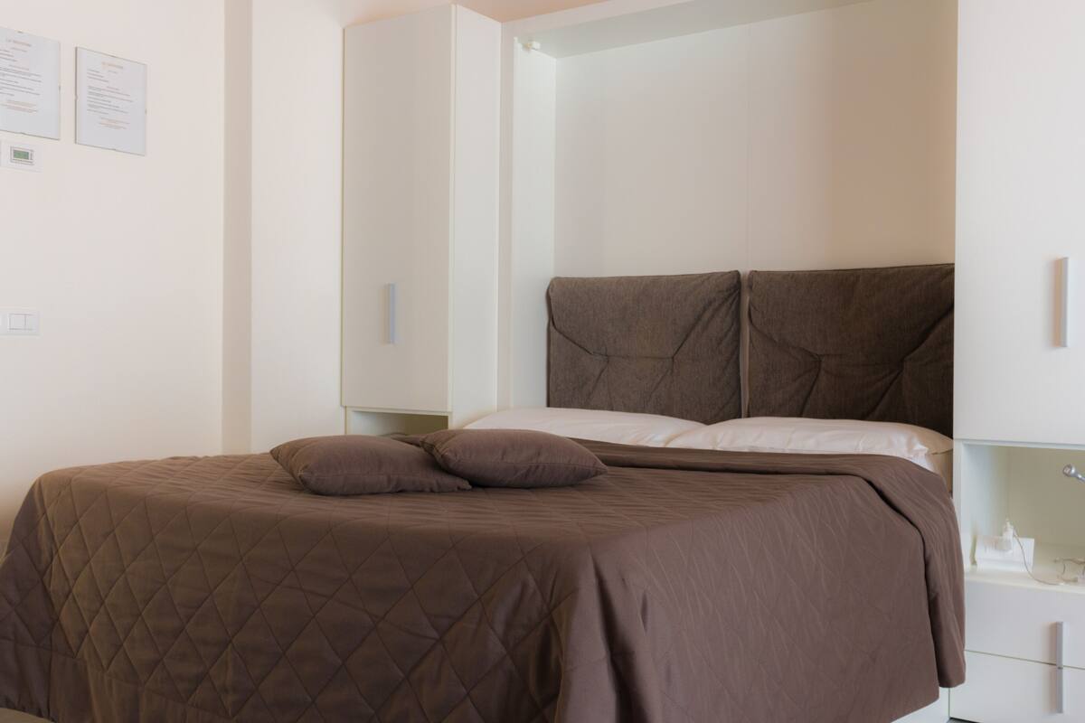Un dormitorio moderno con una cama grande, una mesita de noche y una mesilla.