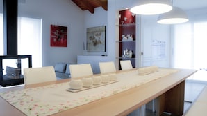 A modern dining area with a long table, white chairs, and decorative vases. - Ca' Belvedere B&B (Silea)