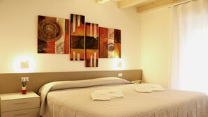 A hotel room with a bed, bedside tables, and wall art. - Ca' Belvedere B&B (Silea)