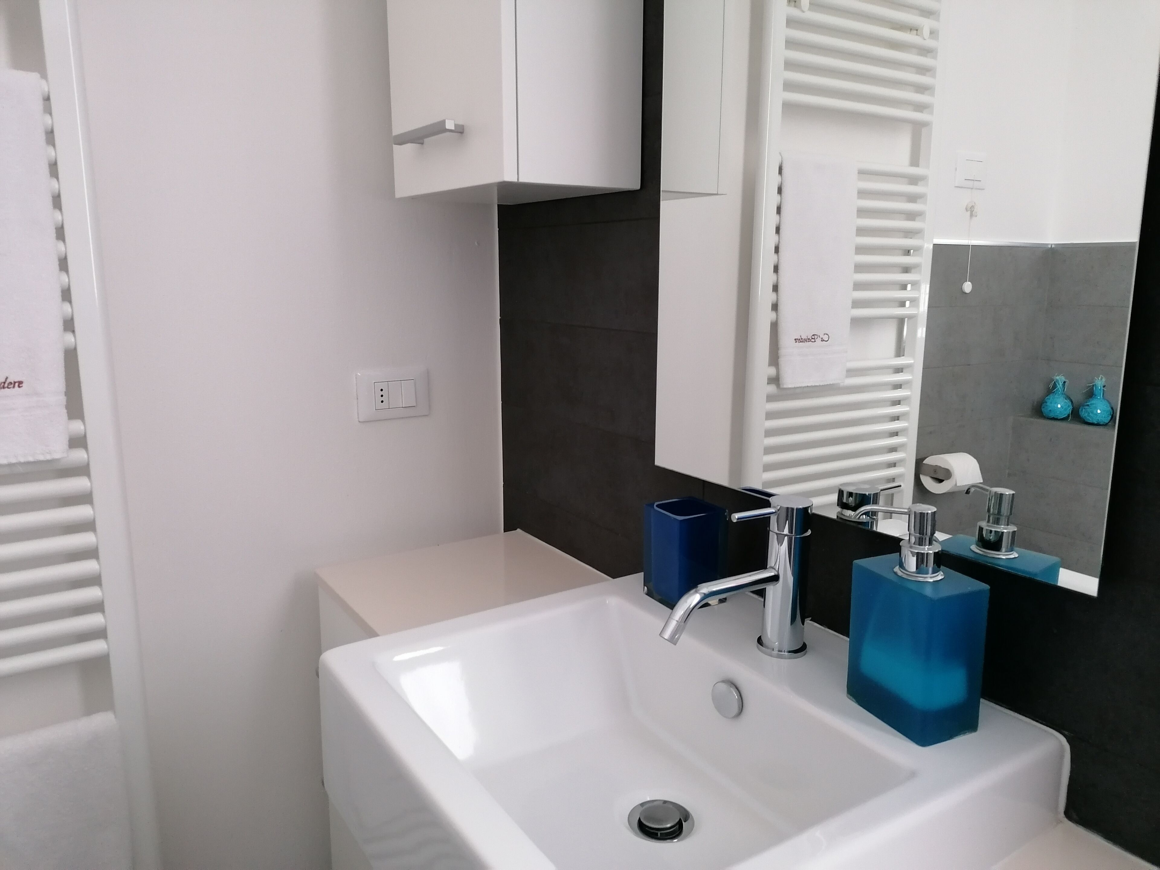 A bathroom with a white sink, a mirror, and a towel rack.