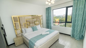 Ein modernes Hotelzimmer mit einem großen Bett, einem Nachttisch, einem Fenster mit Vorhängen und Blick auf die Stadt.
