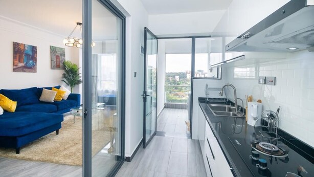 Eine moderne Küche mit einem schwarzen Herd, einer Edelstahl-Spüle und Blick auf die Stadt durch große Fenster.