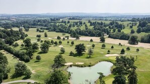 Un parcours de golf comportant plusieurs trous, un étang et des zones boisées environnantes.