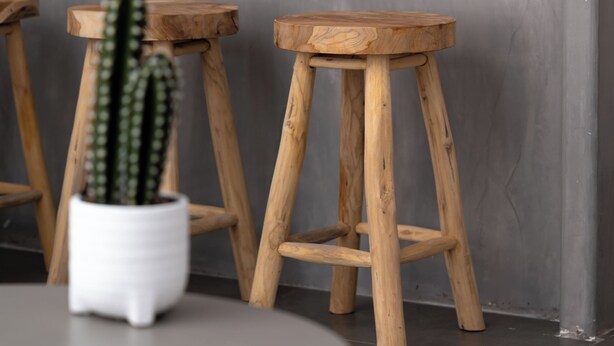 A modern kitchen with a grey countertop, wooden stools, and a cactus plant. - AquaLung Suites (Santorini)