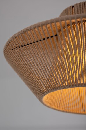 A close-up of a woven, cylindrical lamp with a warm light source inside. - AquaLung Suites (Santorini)