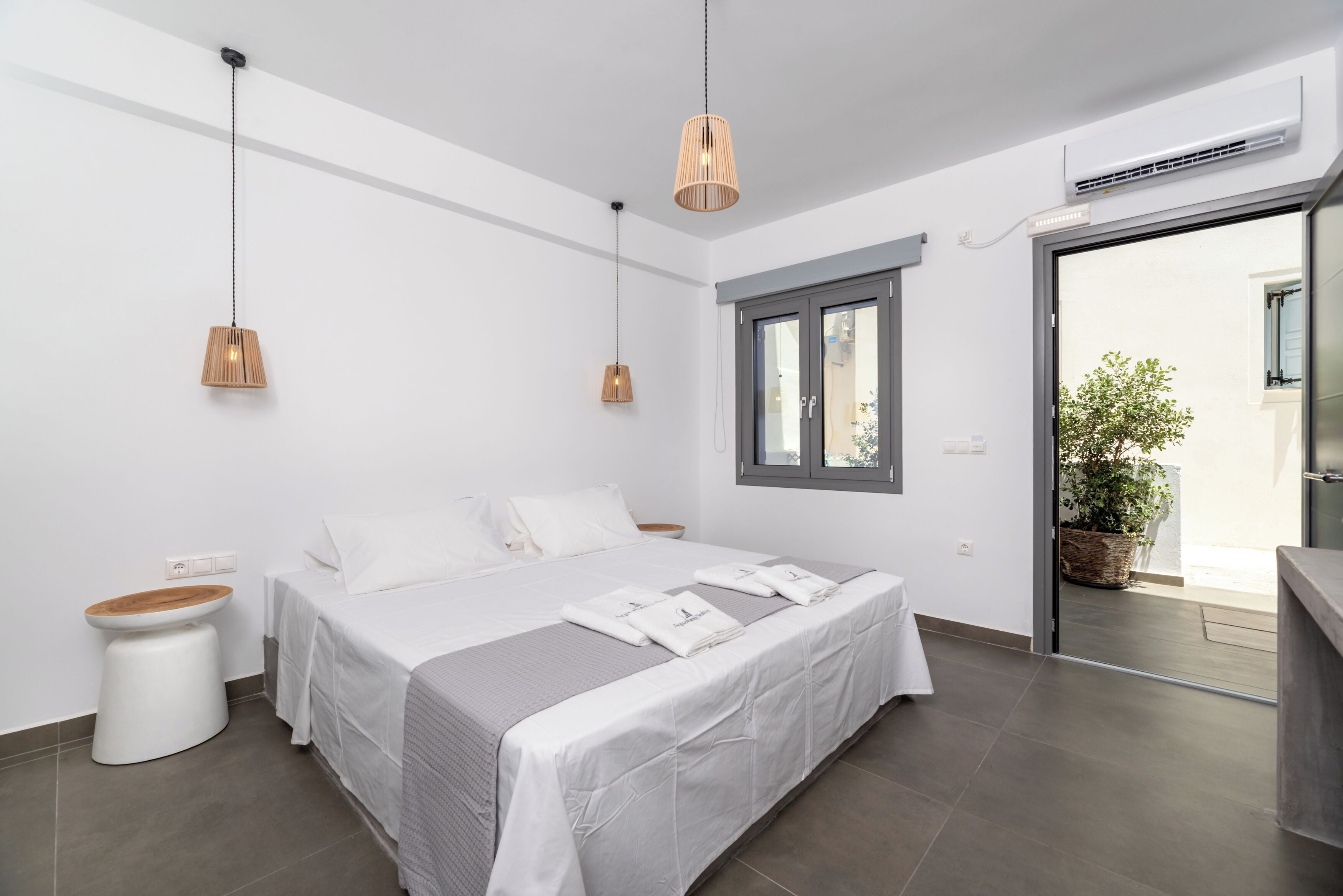 A modern bedroom with a large bed, two bedside tables, a window, and a view of the outdoors.