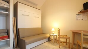 A compact living space with a sofa, a small table, a lamp, and a chair. - Studio with sea view, parking, and pets allowed in La Hague (La Hague)